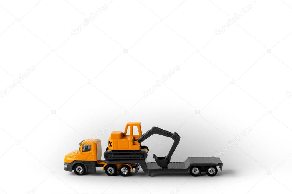 Toy model construction vehicle,cargo yellow low-frame trawl with excavator on trailer,in middle bottom of white background,large copy space.Concept of special equipment for oversized transportation.