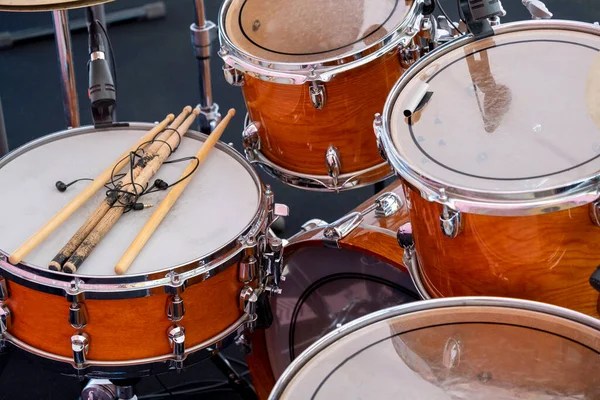 Close up brown wooden drum kit, consisting of cymbals, floor tom-tom, bass and snare drum, hi-hat, not new with battered drumsticks,no people, before concert. Musical instruments and learning concept