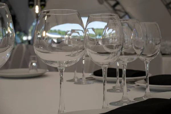 Close up clean empty wine glasses on white served dinner table in party tent on summer sunny day.Concept of party planning manager services. Tableware shop window. Design pattern for glass packaging