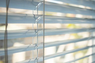 Pencereden gelen güneş ışığı Venedik panjurlarından geliyor..