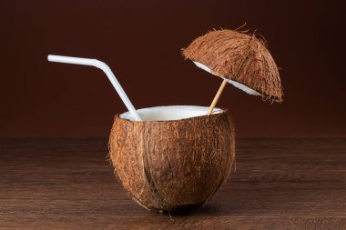 Kahverengi arka planda pipetli hindistan cevizi kokteyli.