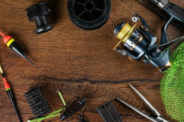 Balık teması. Makara, olta, şamandıra, pusula, yem, bıçak ve tahta zemin ile çerçevelenmiş. Boş alan.