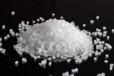 Siyah zemin üzerinde deniz tuzu ya da kaba tuz kristalleri.