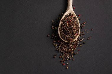 Koyu arkaplanda tahta kaşıkta karışık biber..