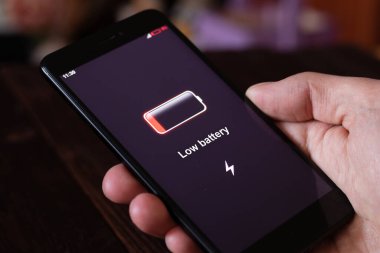 Enerji kavramı: Adam eli düşük pilli akıllı telefonu tutuyor.