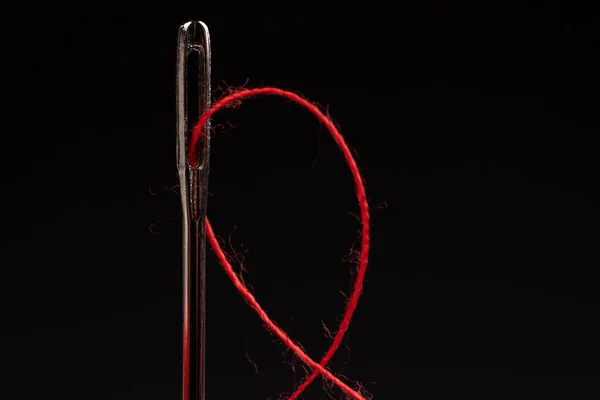 黒い背景の赤い糸と針 — ストック写真