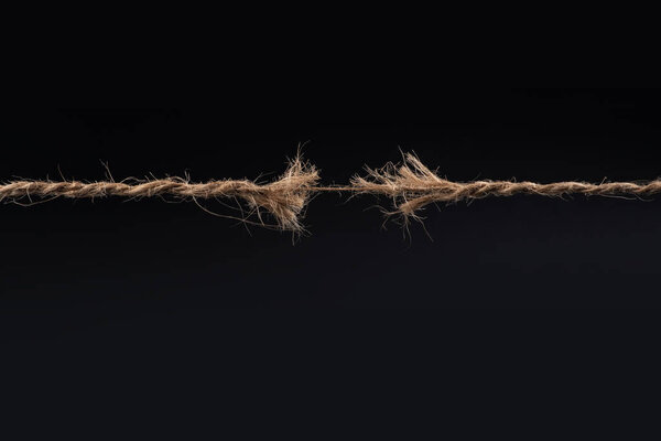 Frayed rope ready to break isolated on black background.