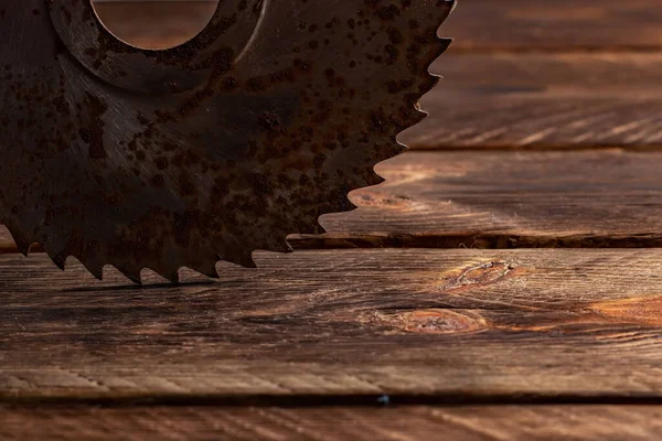 Old circular saw blade on wooden background.