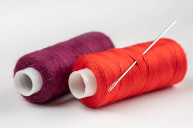 Beyaz arkaplanda iplik ve iğne makaraları.