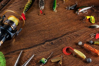 Balık teması. Makara, olta, şamandıra, pusula, yem, bıçak ve tahta zemin ile çerçevelenmiş. Boş alan.