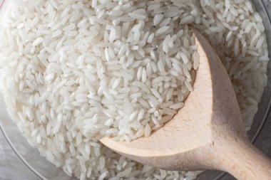 Pirinç arka planında tahta kaşıkta kuru beyaz pirinç..