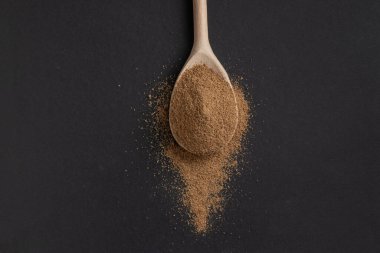 Koyu arkaplanda pudralanmış kişniş ile ahşap kaşık.