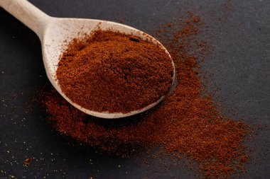 Hindistan baharatlı kırmızı biber tozu. Koyu arkaplanda tahta kaşıkta..