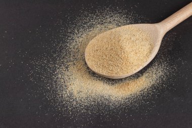 Koyu bir arka planda tahta kaşıkta toz sarımsak..