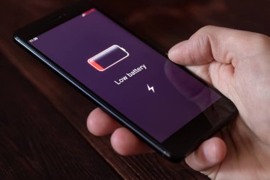 Enerji konsepti: adamın elinde düşük pilli akıllı telefon var. Tüm ekran grafikleri uydurma