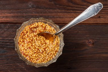 Cam kasede Fransız hardal sosu ve ahşap arka planda metal kaşık..