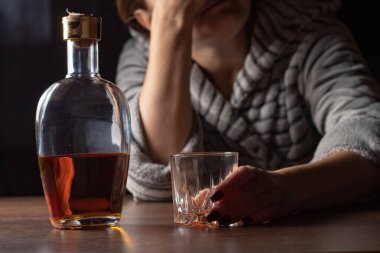 Kadın alkolizmi işte. Kadın kadın evde oturup alkol şişesi içiyor üzgün alkolizm belirtileri ve semptomlar rehabilitasyon sorunları ve iyileşme sorunları.