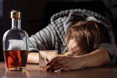 Sarhoş bir kadın viski bardağının yanında uyuyor, alkolik bir kadın alkolden sonra sızmış, alkol problemi, alkol bağımlılığı konsepti....