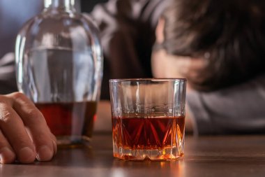 Alkolizm, alkol bağımlılığı ve insan konsepti. Bir bardak viskiyle masada yatan ya da uyuyan erkek alkolik..