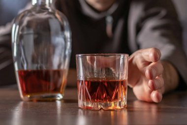 Alkolizm, alkol bağımlılığı ve insan konsepti. Erkek alkolik elini bir bardak alkole uzatıyor..