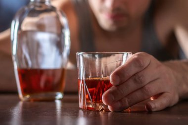 Alkolizm konsepti. Genç adam çok fazla alkol alıyor. Bir bardak viskiyle tişört giymiş alkolik..