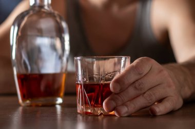 Alkolizm konsepti. Genç adam çok fazla alkol alıyor. Bir bardak viskiyle tişört giymiş alkolik..