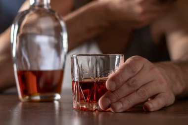 Alkolizm konsepti. Genç adam çok fazla alkol alıyor. Bir bardak viskiyle tişört giymiş alkolik..