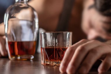Alkolizm, alkol bağımlılığı ve insan konsepti. Bir bardak viskiyle masada yatan ya da uyuyan erkek alkolik..