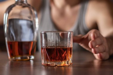 Alkolizm, alkol bağımlılığı ve insan konsepti. Erkek alkolik elini bir bardak alkole uzatıyor..