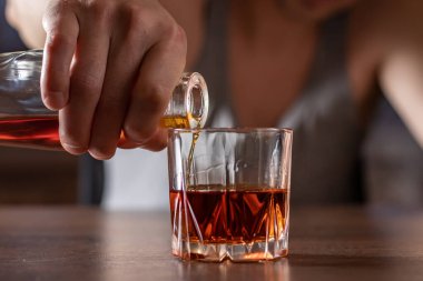 Alkolizm konsepti. Genç adam çok fazla alkol alıyor. Tişörtlü alkolik bardağa alkol döküyor..