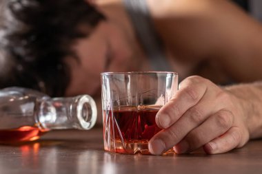 Alkolizm, alkol bağımlılığı ve insan konsepti. Bir bardak viskiyle masada yatan ya da uyuyan erkek alkolik..