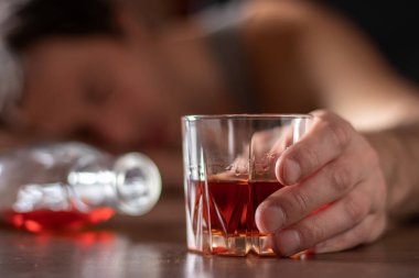 Alkolizm, alkol bağımlılığı ve insan konsepti. Bir bardak viskiyle masada yatan ya da uyuyan erkek alkolik..