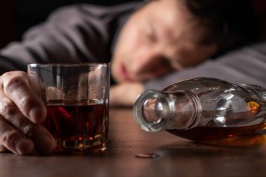 Alkolizm, alkol bağımlılığı ve insan konsepti. Bir bardak viskiyle masada yatan ya da uyuyan erkek alkolik..