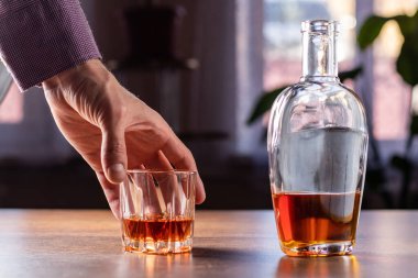 Alkolizm, erkek eli bir bardak alkolü alır, sadece viski bardağını tutar. Alkol bağımlılığının tedavisi, taciz sorunu alkolizm kavramı.