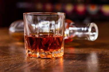 Masanın üzerinde bir bardak viski ve bir şişe.