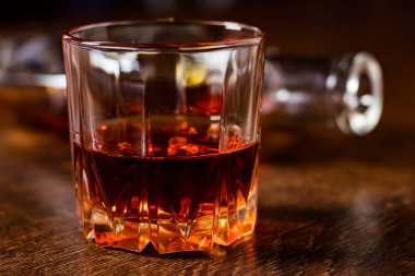 Masanın üzerinde bir bardak viski ve bir şişe.