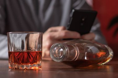 Alkolizm. Alkol bağımlılığı ve insanların konsepti. Akıllı telefonlu ve arkadaşlarıyla viski içen alkolik bir erkek.