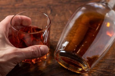 Arka planda viski bardağı tutan adam..