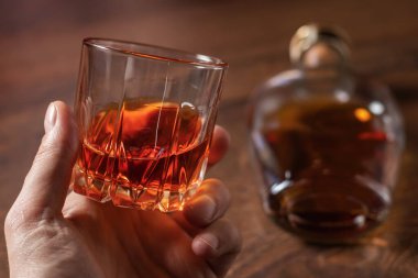 Arka planda viski bardağı tutan adam..
