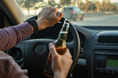 Adam araba sürerken bira içiyor. İçkili araba kullanma.