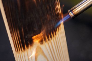 Karanlık bir arka planda, yanan bir odun ve gaz ocağı..