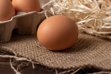 Çuval bezinde kahverengi yumurtalar ve ahşap arka plan.