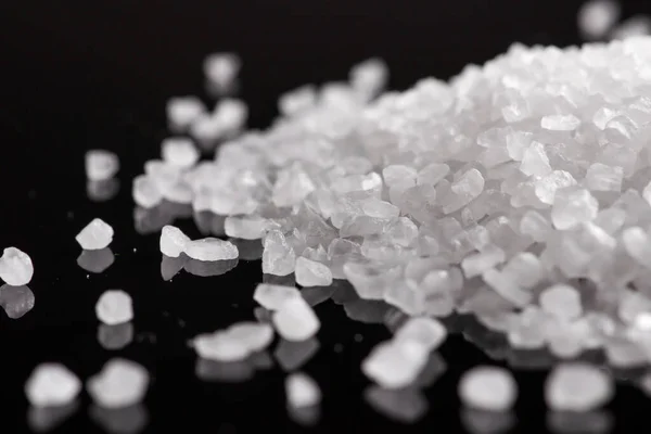 Close-up of macro crystals of sea salt or coarse salt on black background.