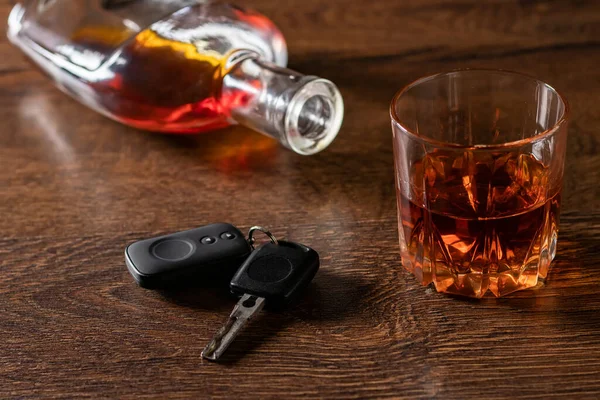 Bardakta alkol, ahşap masada araba anahtarı. Sarhoş araba kullanma konsepti