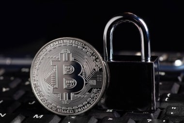 Bitcoin güvenlik konsepti. Bilgisayar klavyesinde asma kilit olan gümüş para