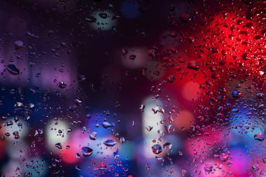 Terli camda bir damla yoğuşma var. Arka planda soğuk sisli cam gece ışıkları.