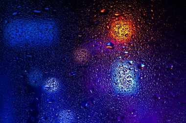 Terli camda bir damla yoğuşma var. Arka planda soğuk sisli cam gece ışıkları.