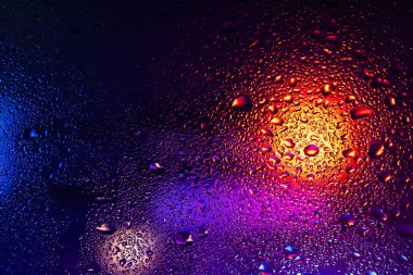 Terli camda bir damla yoğuşma var. Arka planda soğuk sisli cam gece ışıkları.