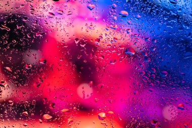 Terli camda bir damla yoğuşma var. Arka planda soğuk sisli cam gece ışıkları.