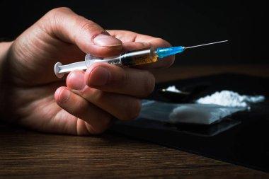 Elinde uyuşturucu şırıngası var. Şırıngada bir doz daha uyuşturucu bulunan bir uyuşturucu bağımlısı. Bağımlı adam, uyuşturucu karşıtı konsept. erkek uyuşturucu bağımlısı.
